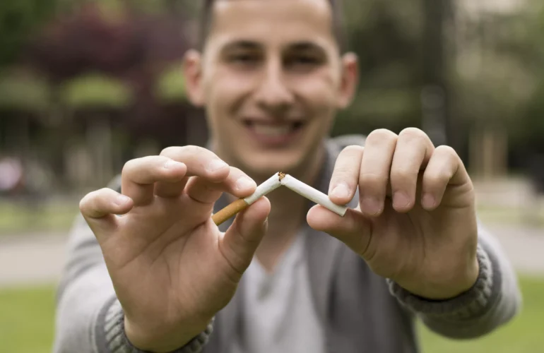 Hombre joven rompiendo un cigarro, puede que haya decidido hacerlo después de conocer cómo al dejar de fumar se recuperan las encías